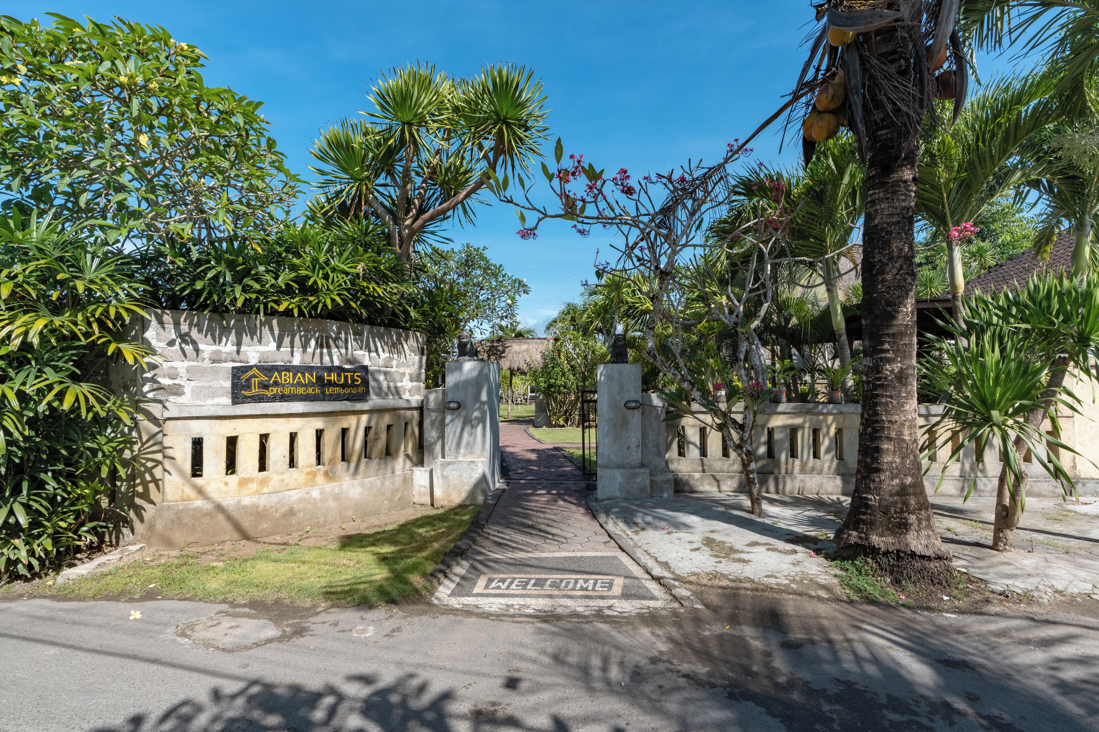 A gated entrance with a sign for 'ABIAN HUTS Dreambeach Lembongan.'