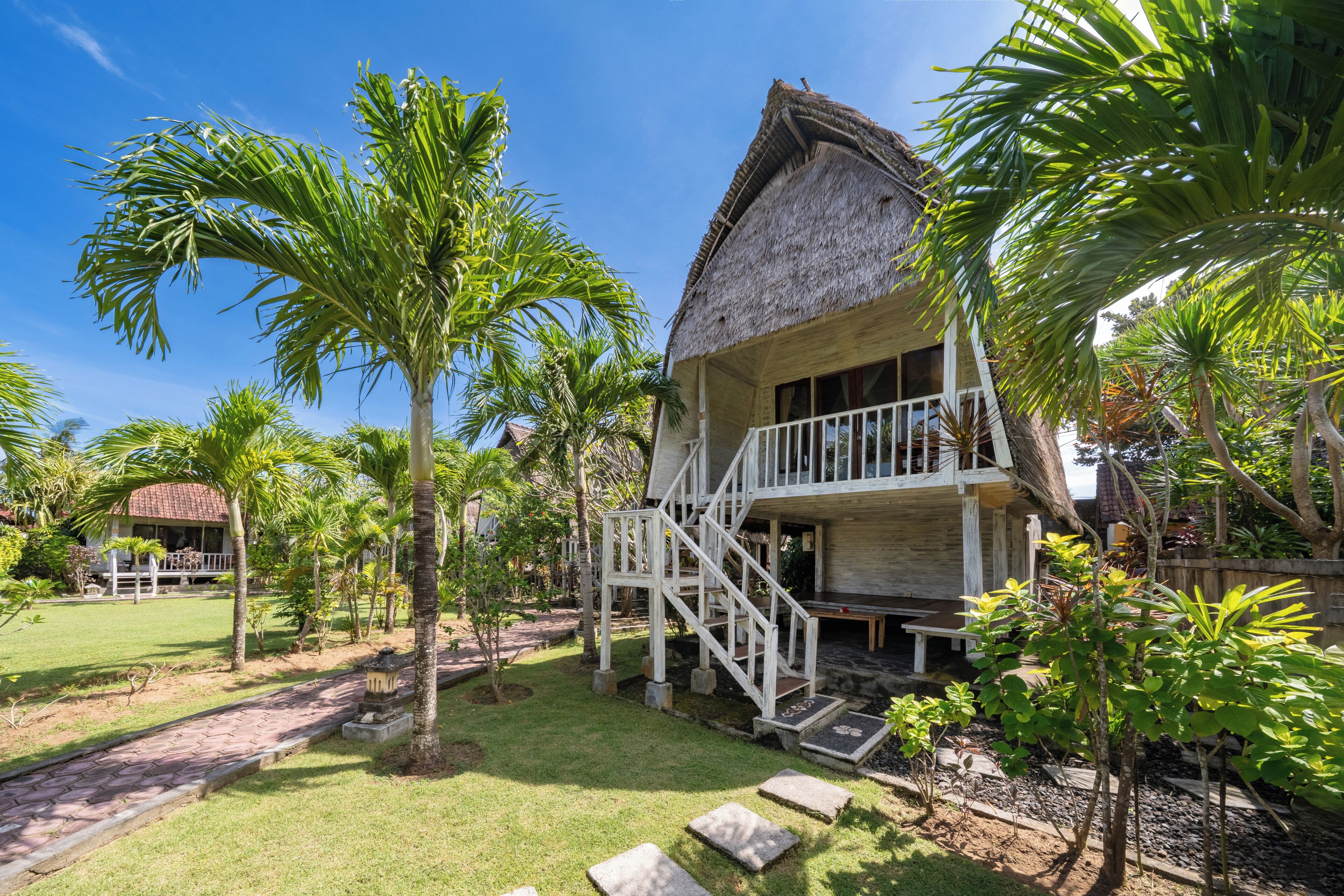 A house with a thatched roof, a wooden staircase, and a front porch.