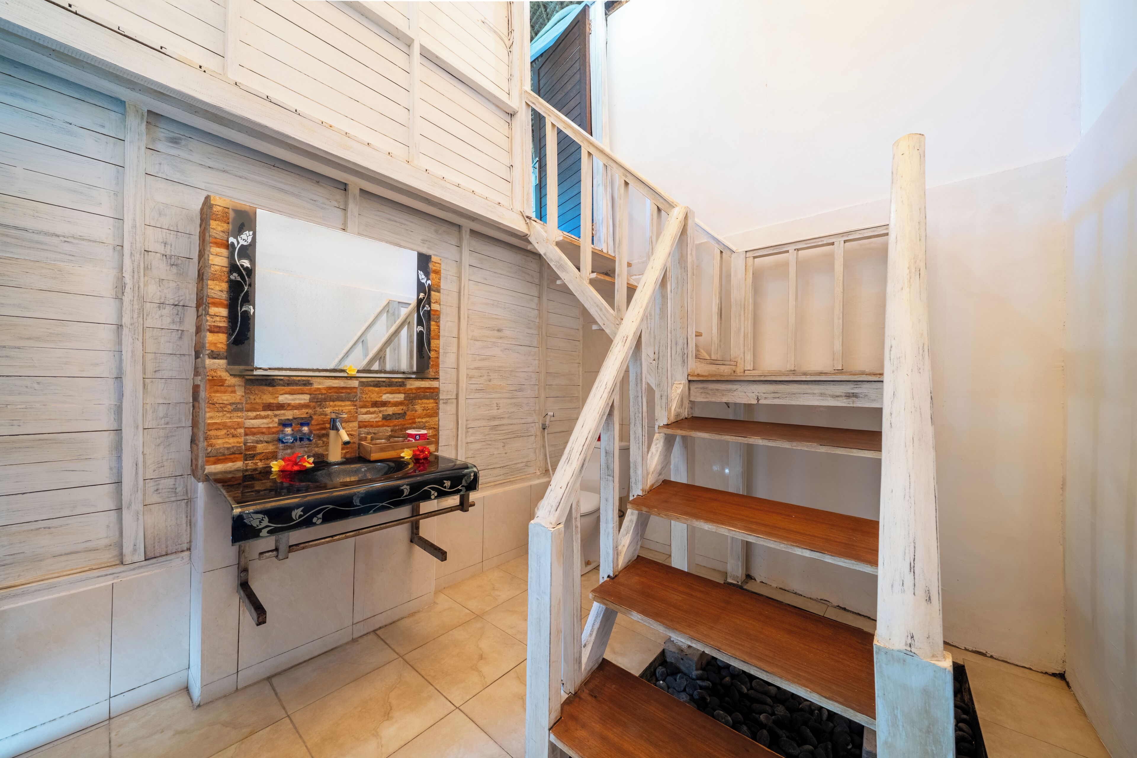 Une salle de bain avec un meuble-lavabo en bois, un miroir et un escalier.