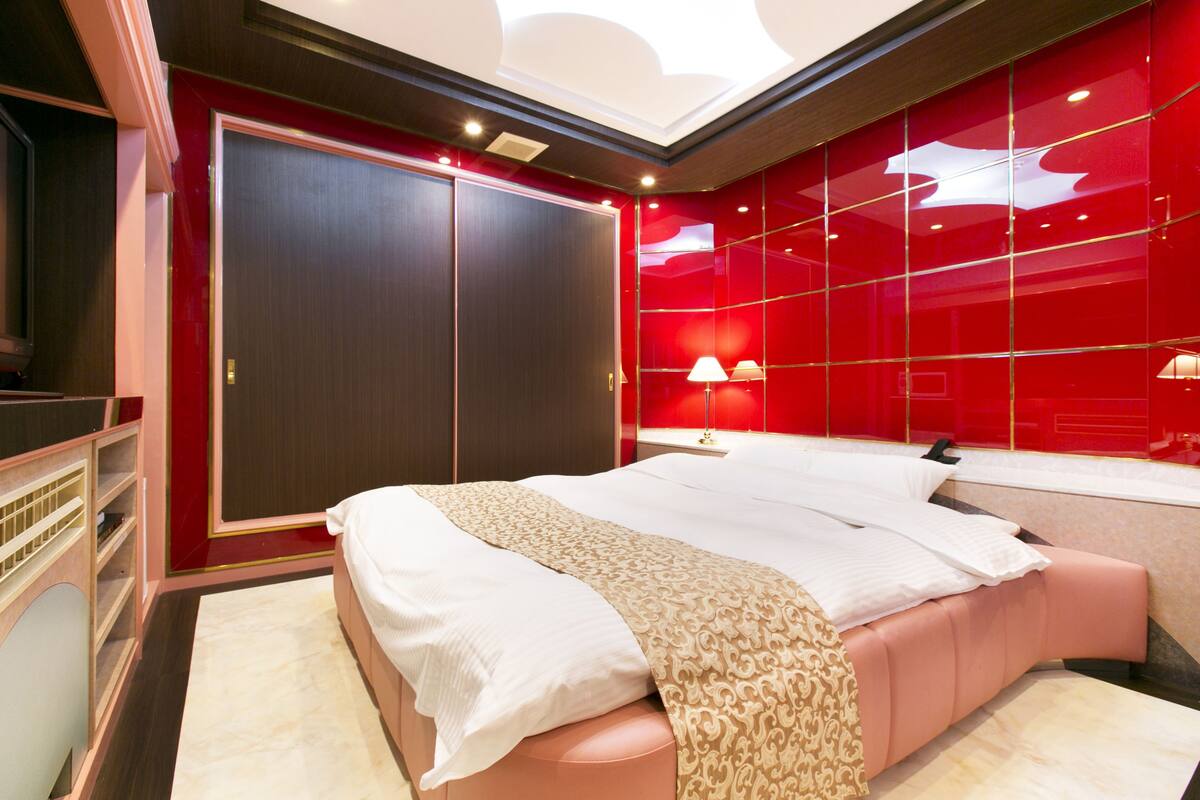 Ein modernes Schlafzimmer mit einem großen Bett, einem Kleiderschrank und einer roten Akzentwand.