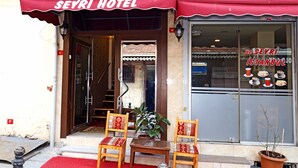 The Seyri Hotel entrance with a red awning, two wooden chairs with patterned cushions, a small table, and a potted plant. - Seyri Istanbul Hotel (Istanbul)