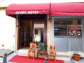 The Seyri Hotel entrance with a red awning, two wooden chairs with patterned cushions, a small table, and a potted plant. - Seyri Istanbul Hotel (Istanbul)