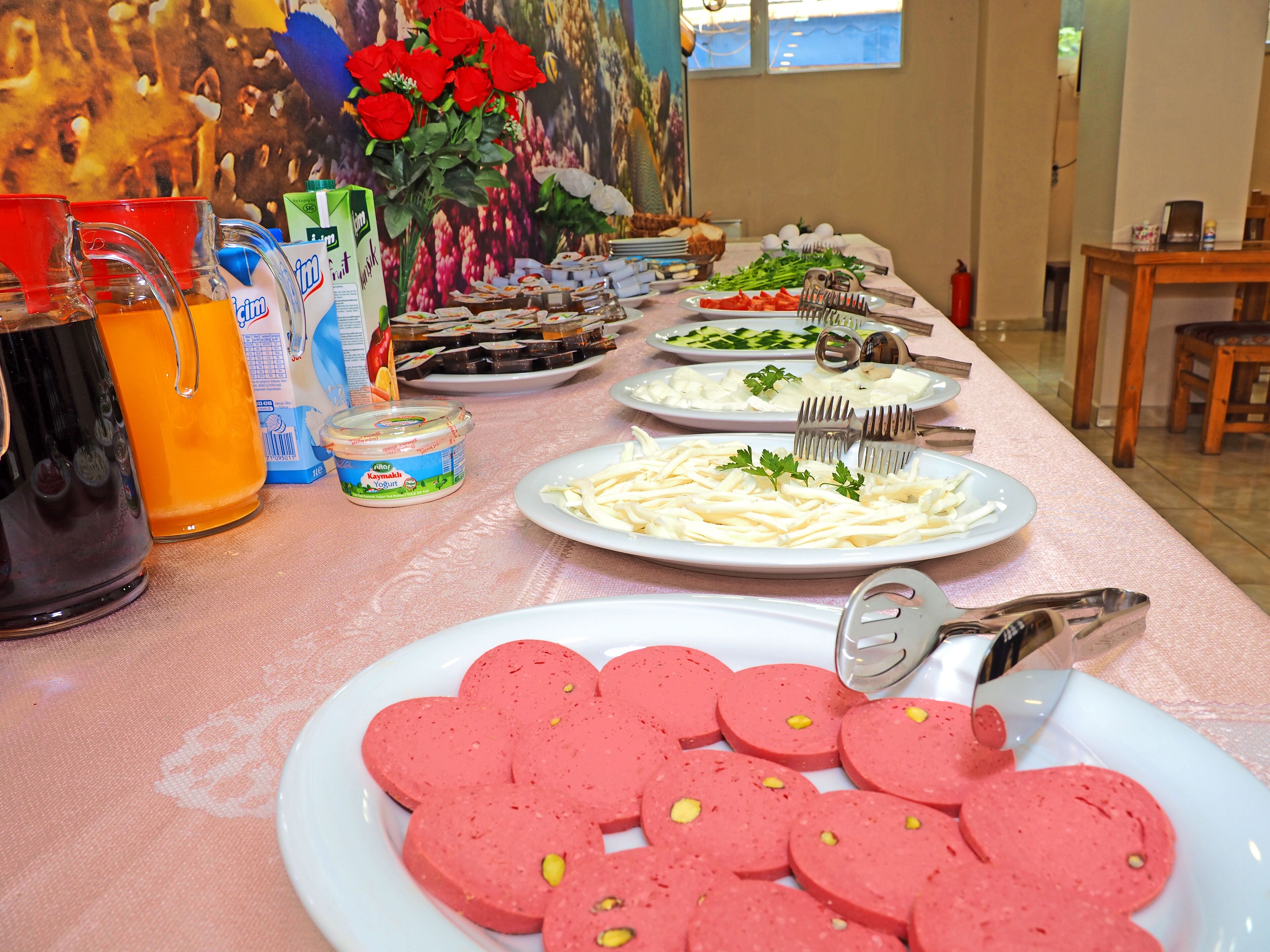 A table set with various food items, including sliced sausages, plates of vegetables, and condiments.