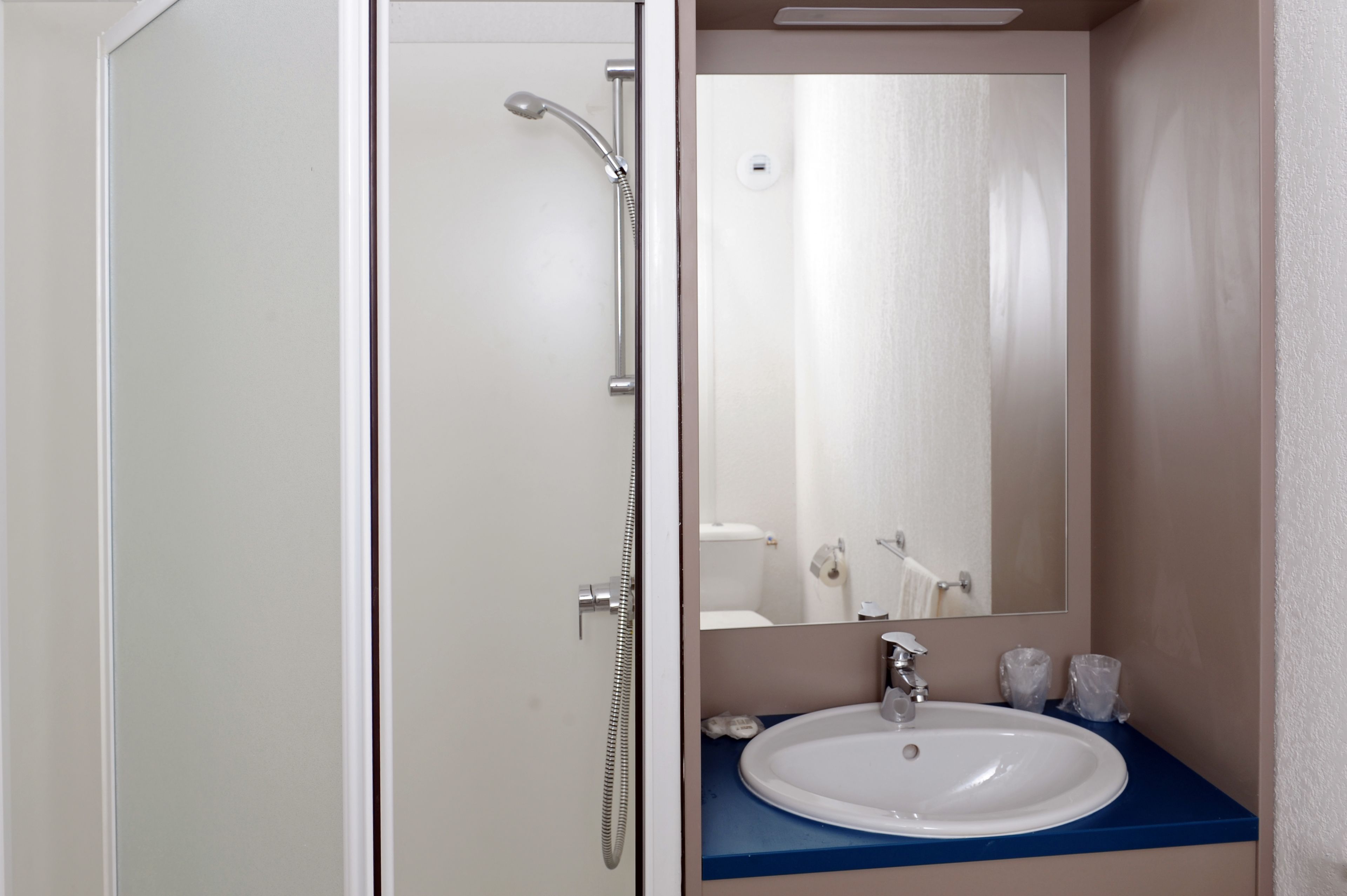 Ein Badezimmer mit einem weißen Waschbecken, einer blauen Arbeitsplatte und einem Spiegel darüber.