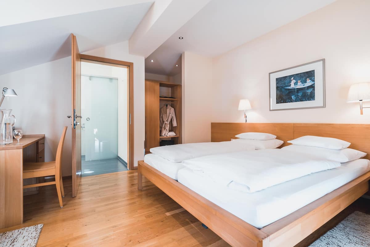 A bedroom with a wooden bed, a desk, a chair, and a wardrobe.