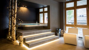 Une salle de bain moderne avec une baignoire sur pieds, un escalier en bois et un coin salon offrant une vue sur l’extérieur.