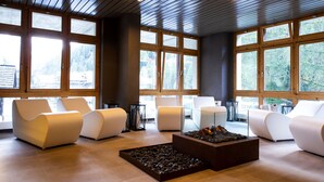 Un intérieur moderne avec de grandes fenêtres, des canapés blancs et un foyer central.
