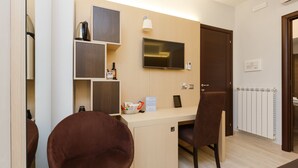 A modern room with a wooden desk, a flat-screen TV, a brown chair, and a door. - Domus Terenzio (Rome)