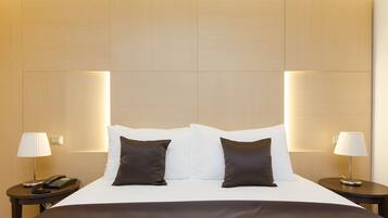 A hotel room with a large bed, two bedside tables, and lamps.