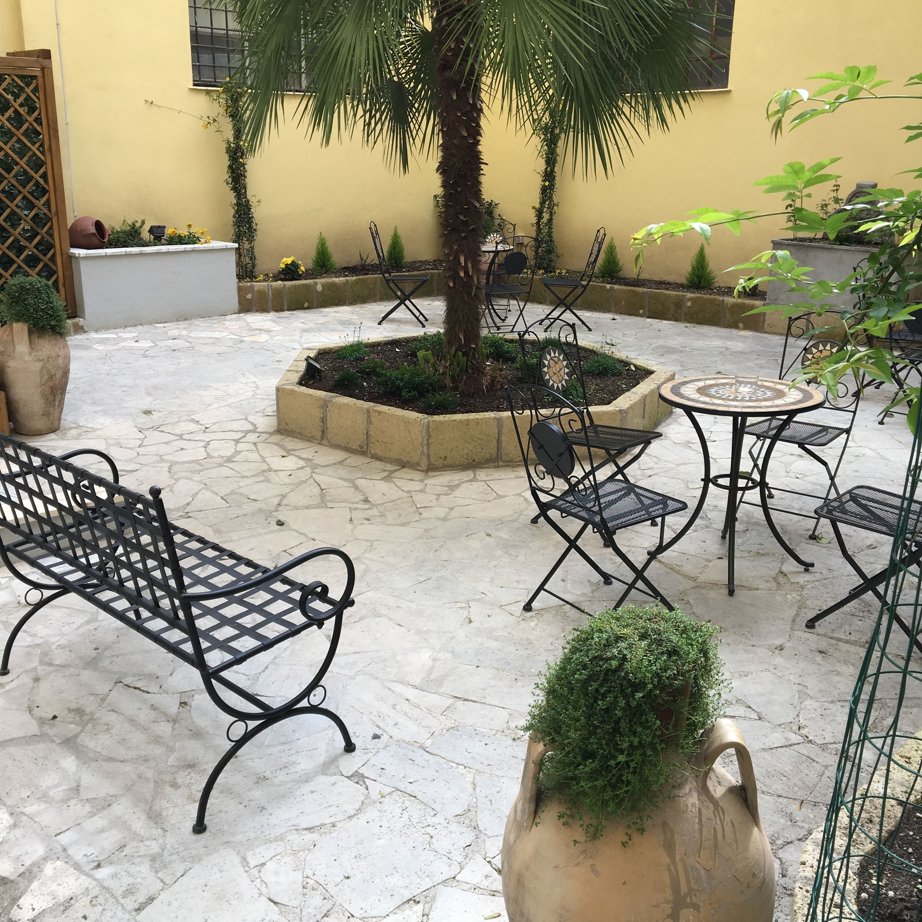 An outdoor patio area with stone flooring, metal furniture, and potted plants.