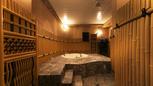 A stone-floored bathroom with a bathtub, bamboo walls, and a wooden ladder. - Hotel Lotus Sakai - Adults Only (Sakai)