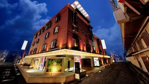 A multi-story hotel with a prominent sign on the rooftop, a ground-level entrance with a reception area, and a visible staircase leading to the upper floors. - Hotel Lotus Sakai - Adults Only (Sakai)