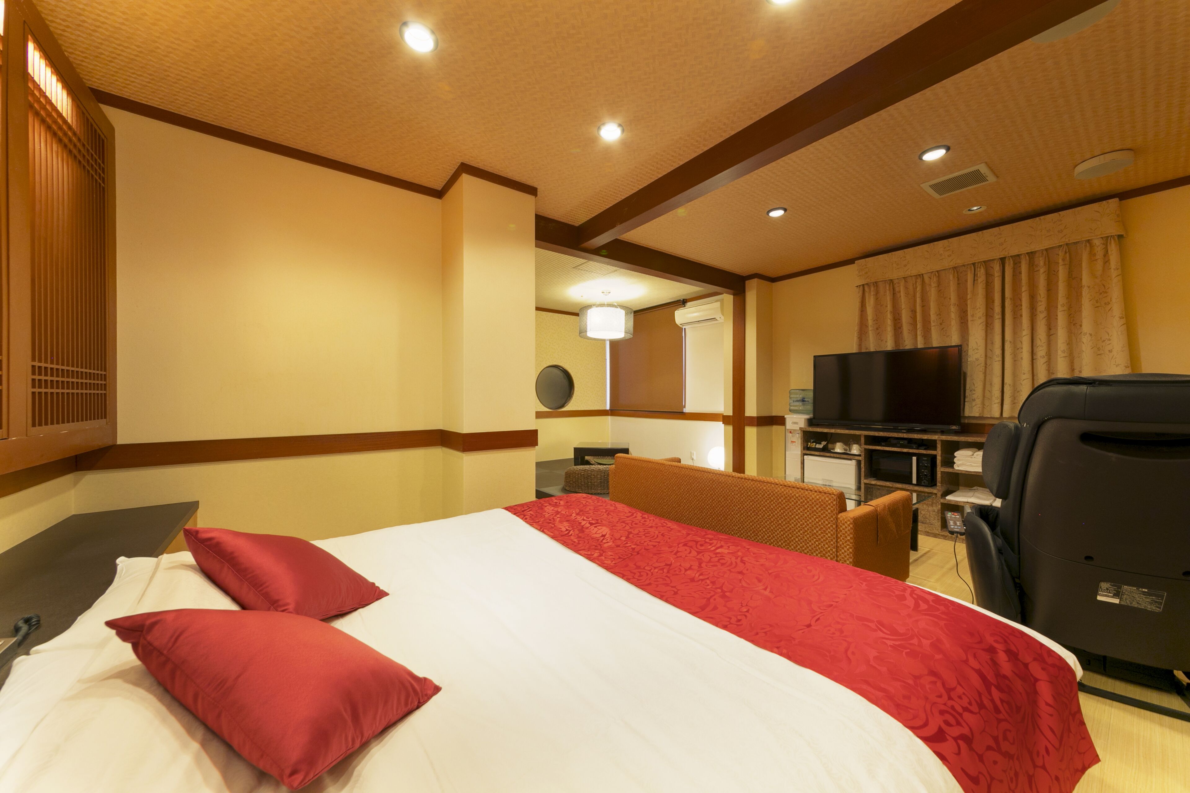 Una camera d'albergo con un letto grande, una televisione, una scrivania e una sedia.