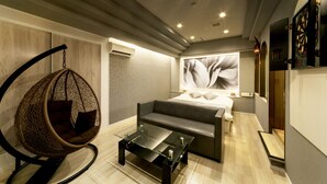 A modern bedroom with a bed, a hanging chair, and a glass coffee table. - Hotel Lotus Sakai - Adults Only (Sakai)