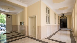 Un pasillo con piso claro, una puerta y una ventana con rejas.