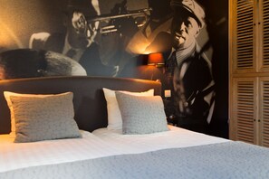 Una cama bien hecha con dos almohadas, un cabecero y un mural en la pared de un trompetista.