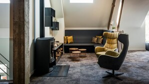 A modern living room with a black sofa, a yellow armchair, and a fireplace. - Boskapelhoeve Charming Hotel (Buggenhout)