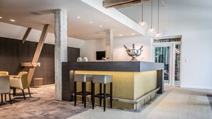 A modern bar area with a concrete pillar, two bar stools, and a copper decorative bowl. - Boskapelhoeve Charming Hotel (Buggenhout)