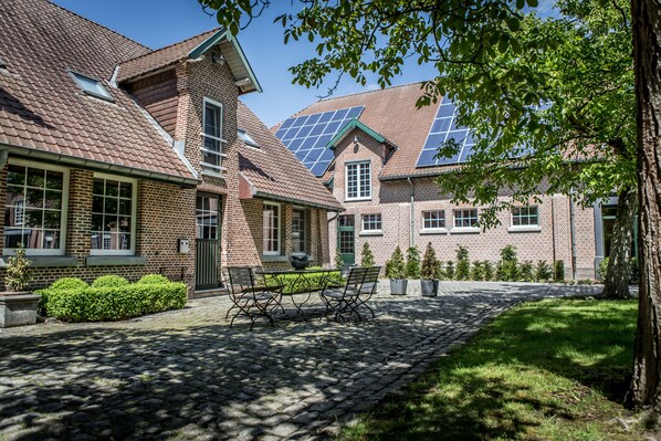 A courtyard with a cobblestone path, a bench, and a table.