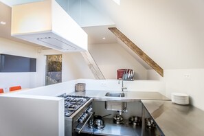 Una cocina moderna con estufa a gas, encimeras de acero inoxidable y un lavamanos empotrado.