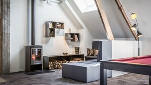 A loft-style room with a built-in wood stove, a pool table, and a skylight. - Boskapelhoeve Charming Hotel (Buggenhout)