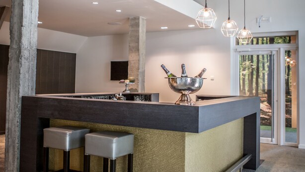 A modern kitchen with a central island, bar stools, pendant lighting, and a view of the outdoors. - Boskapelhoeve Charming Hotel (Buggenhout)