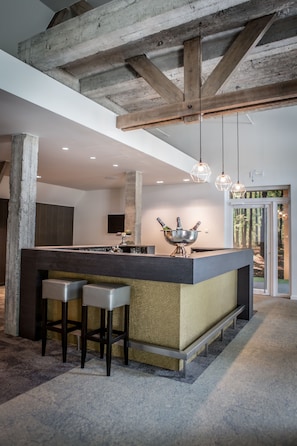 A modern kitchen with a central island, bar stools, pendant lighting, and a view of the outdoors.