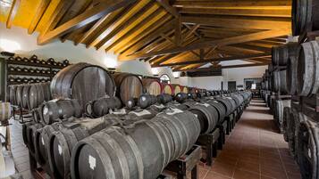 A warehouse with rows of wooden barrels on shelves and a high wooden ceiling.