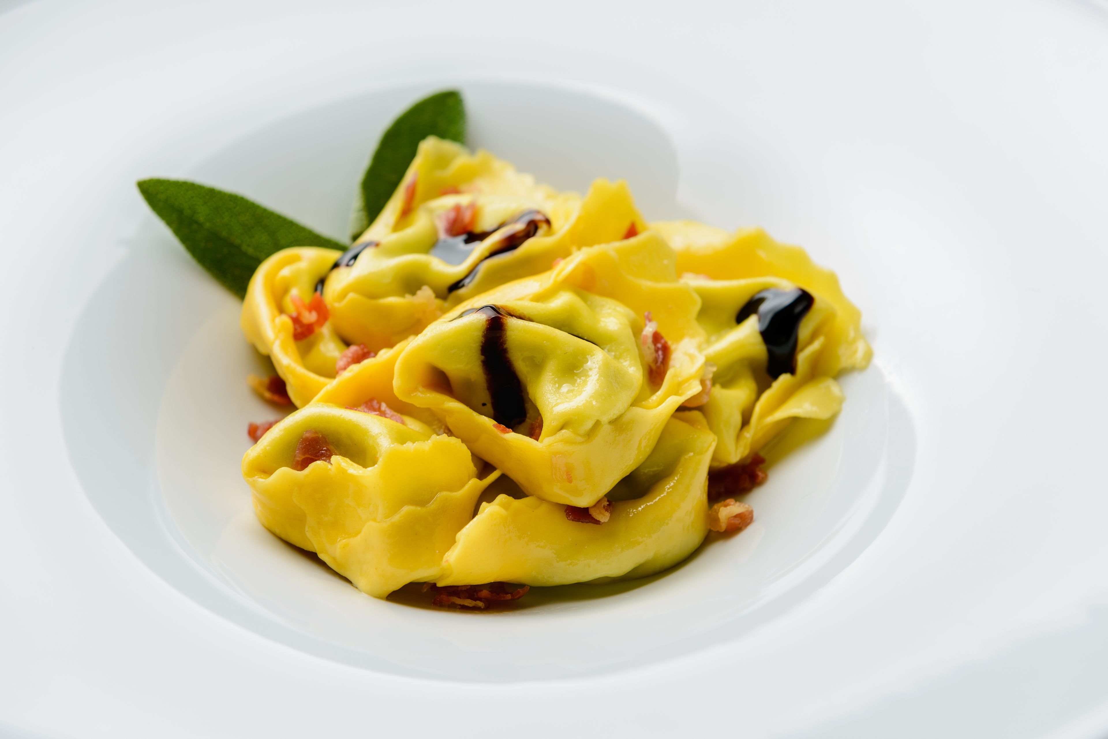 Ein Teller Ravioli mit Soße und Garnitur.