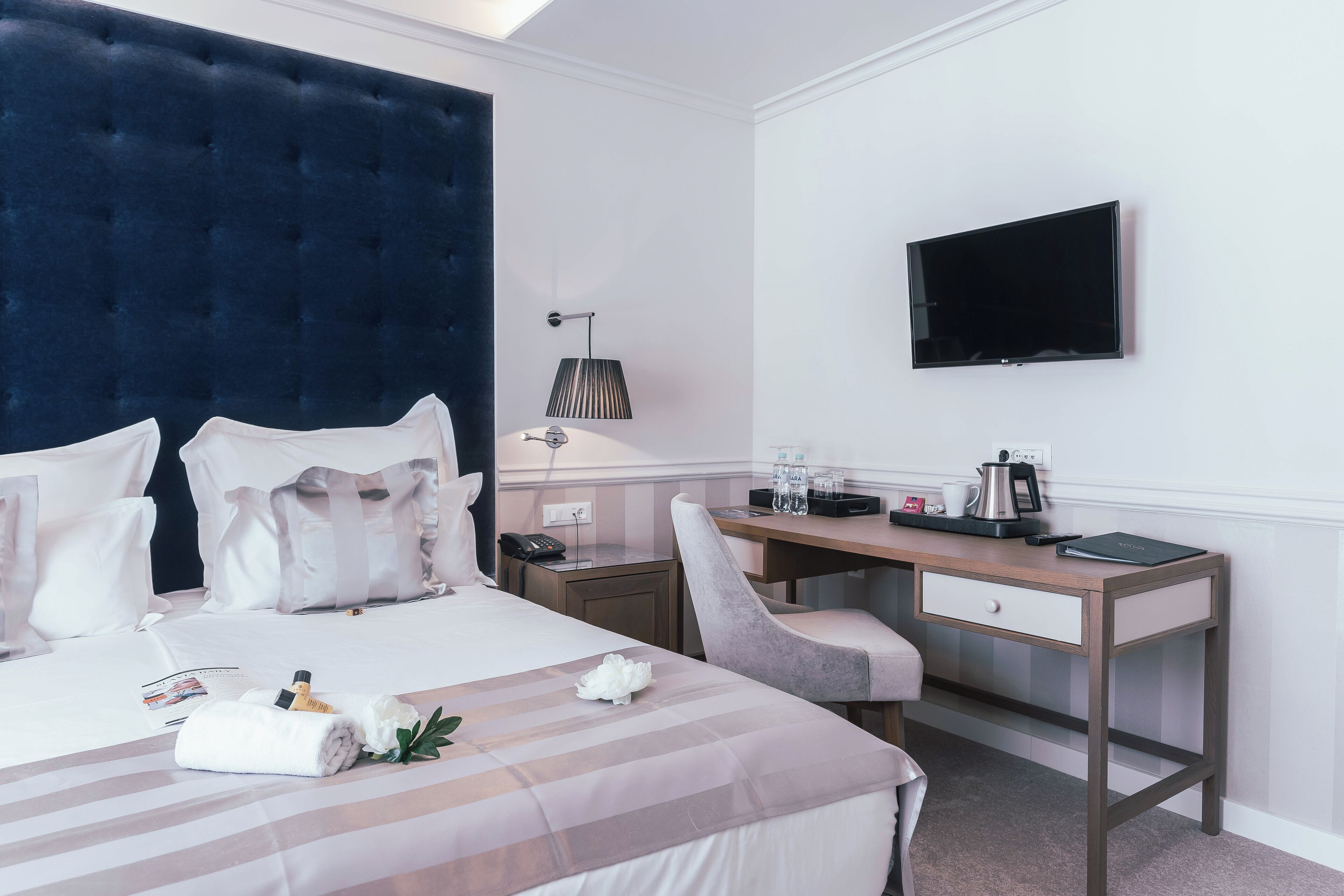 Una camera d'albergo con un letto grande, una scrivania, una sedia, una TV e una lampada.