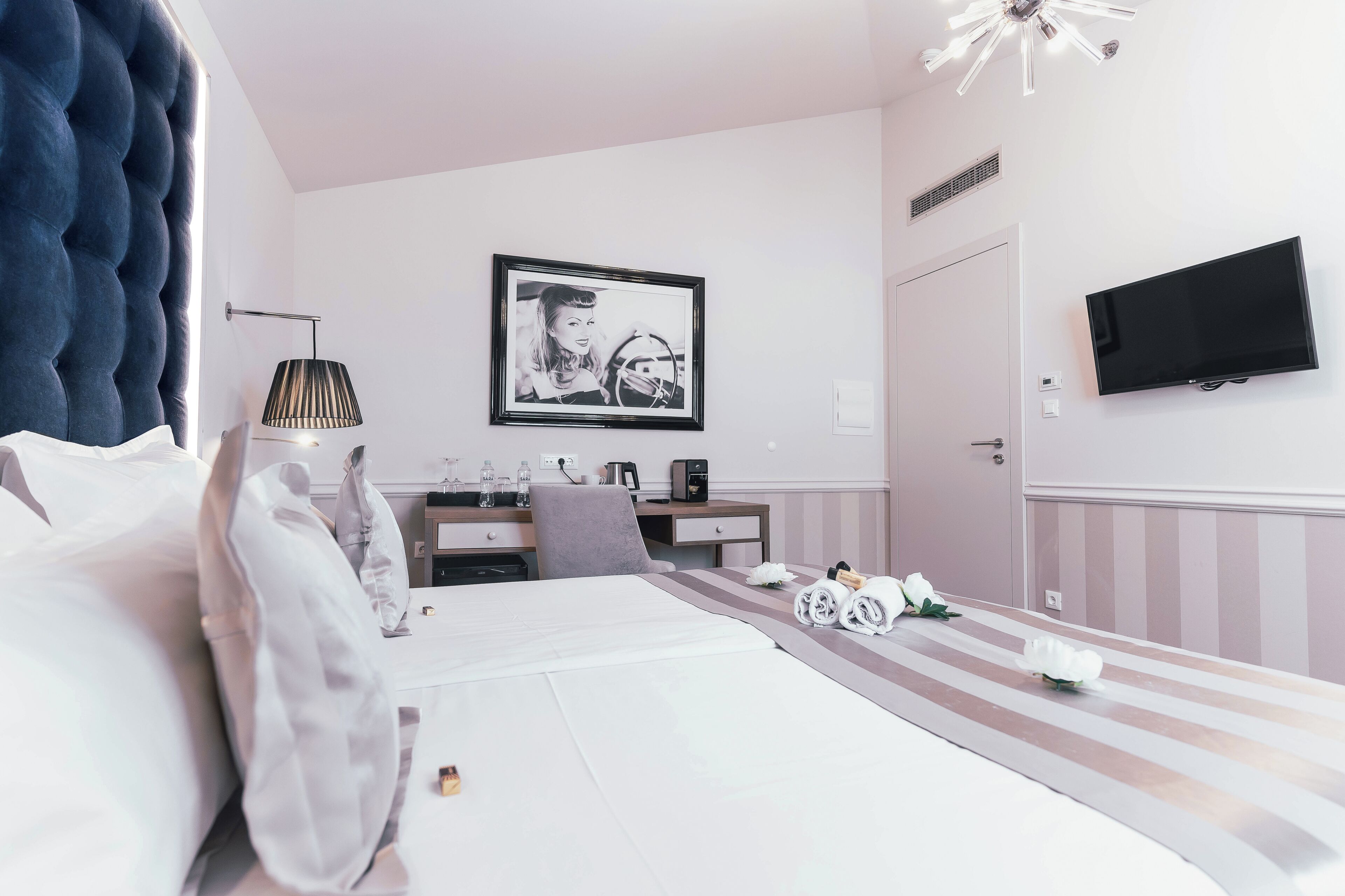 Una habitación de hotel moderna con una cama grande, un escritorio, un televisor de pantalla plana y un cuadro en la pared.