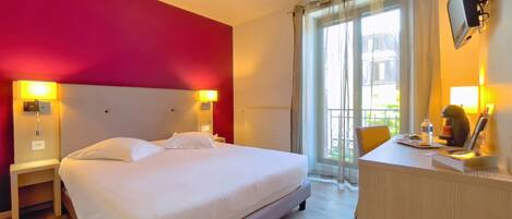 A hotel room with a bed, bedside tables, a desk, and a chair.