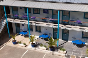 A motel with a two-story balcony, outdoor seating area, and potted plants. - Hôtel de la Gare (Quimper)