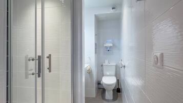 Un baño moderno con cabina de ducha de vidrio, inodoro y bidé de pared.