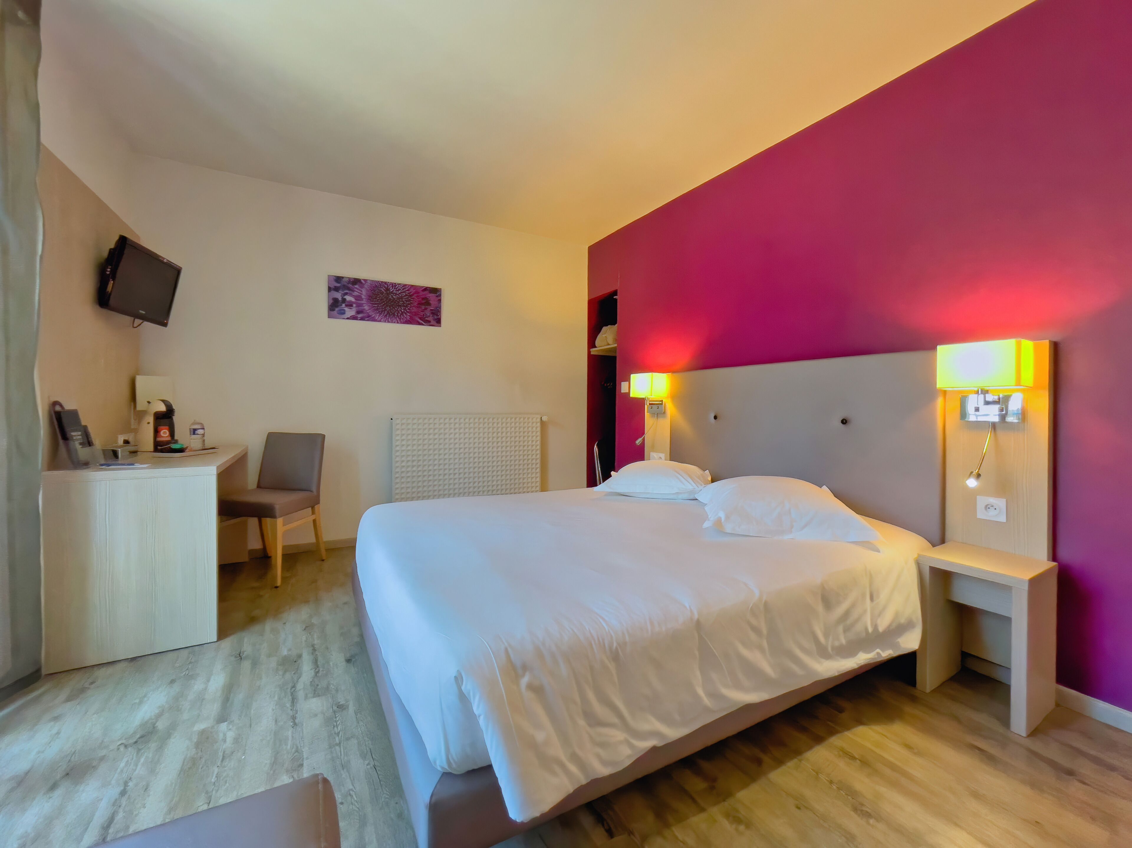 Une chambre d’hôtel équipée d’un lit, de tables de chevet, d’un bureau, d’une chaise, d’une télévision et d’un radiateur.