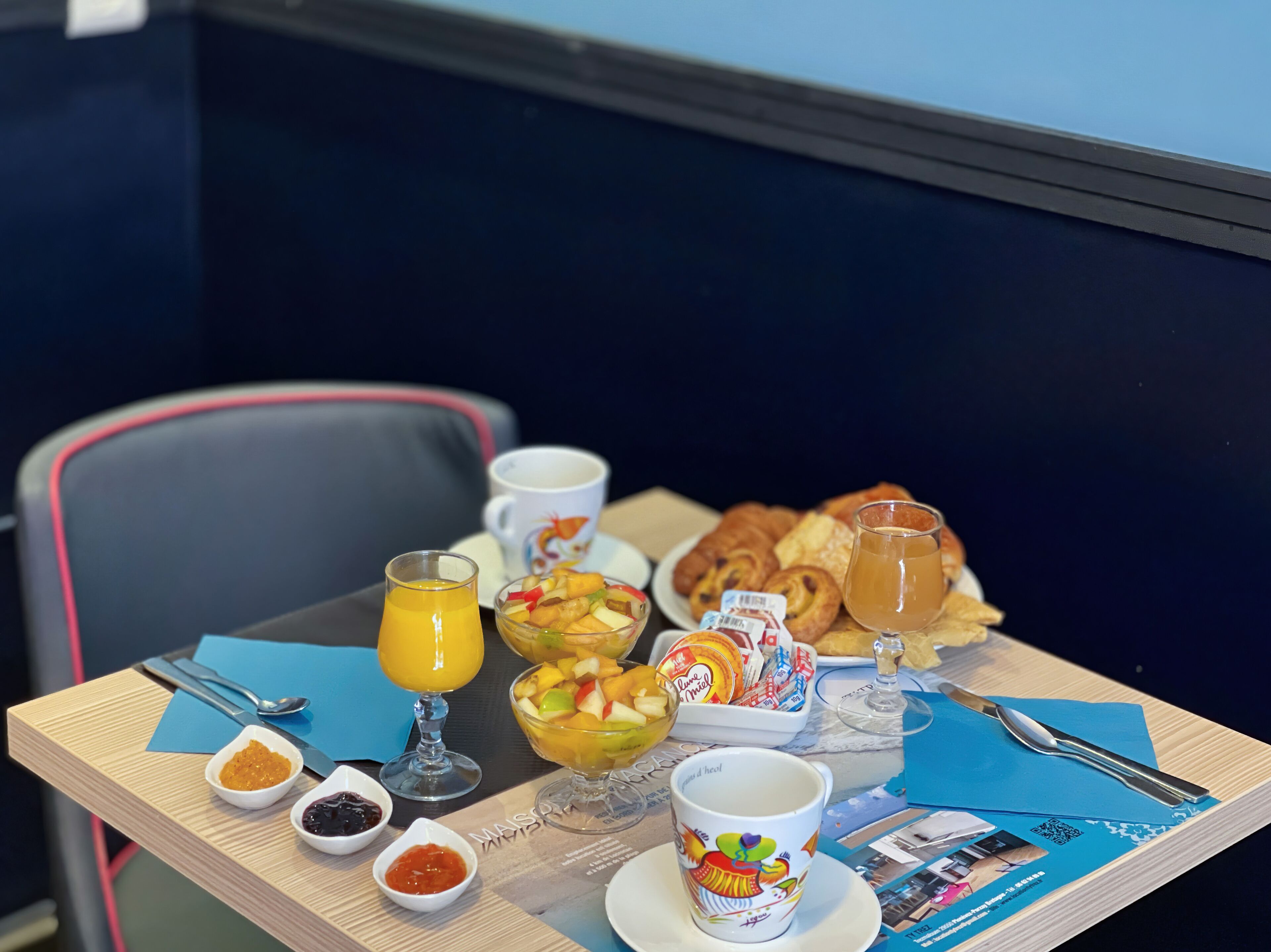A breakfast table with various food items, including croissants, fruit, and a cup of coffee.