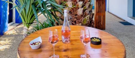 Una mesa de madera con una botella y copas de vino tinto, un bol de aceitunas y un cuenco pequeño de frutos secos.