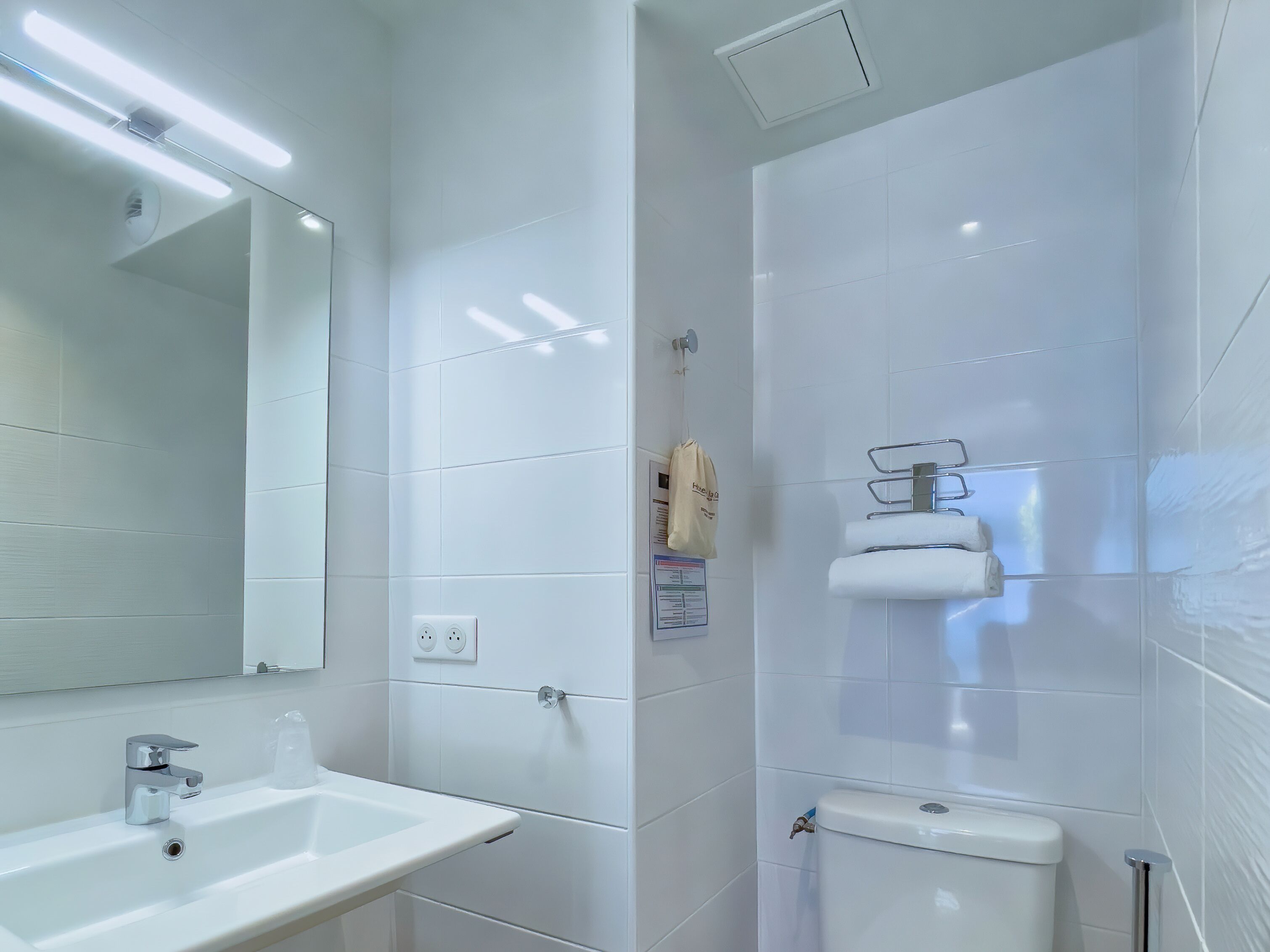 A modern bathroom with a white sink, mirror, and toilet.