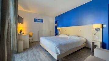 A modern hotel room with a large bed, a desk, and a chair.