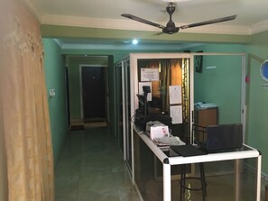 A hallway with a ceiling fan, a desk with papers, and a door leading to another room. - Secrets Hotel (Accra)
