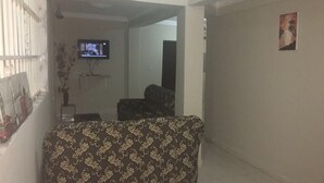 Ein Wohnzimmer mit einem gemusterten Sofa, einem Fernseher und einem Gemälde an der Wand.