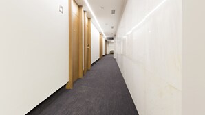 A long, narrow hallway with wooden doors on one side and white walls on the other. - Orasac Garni (Belgrade)