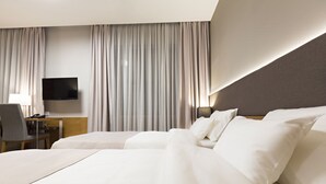 A hotel room with a large bed, a desk with a chair, a flat-screen TV, and a large window with curtains. - Orasac Garni (Belgrade)