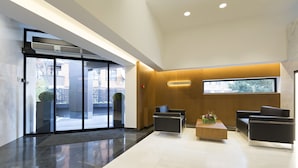 A modern lobby with a glass entrance, a reception desk, and seating area. - Orasac Garni (Belgrade)
