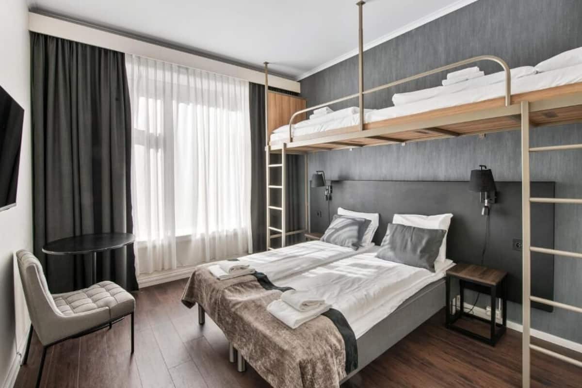 Quarto de hotel moderno com uma cama beliche, uma escrivaninha e uma cadeira.