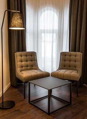 Una habitación con dos sillones capitonados, una mesita y una lámpara de pie.