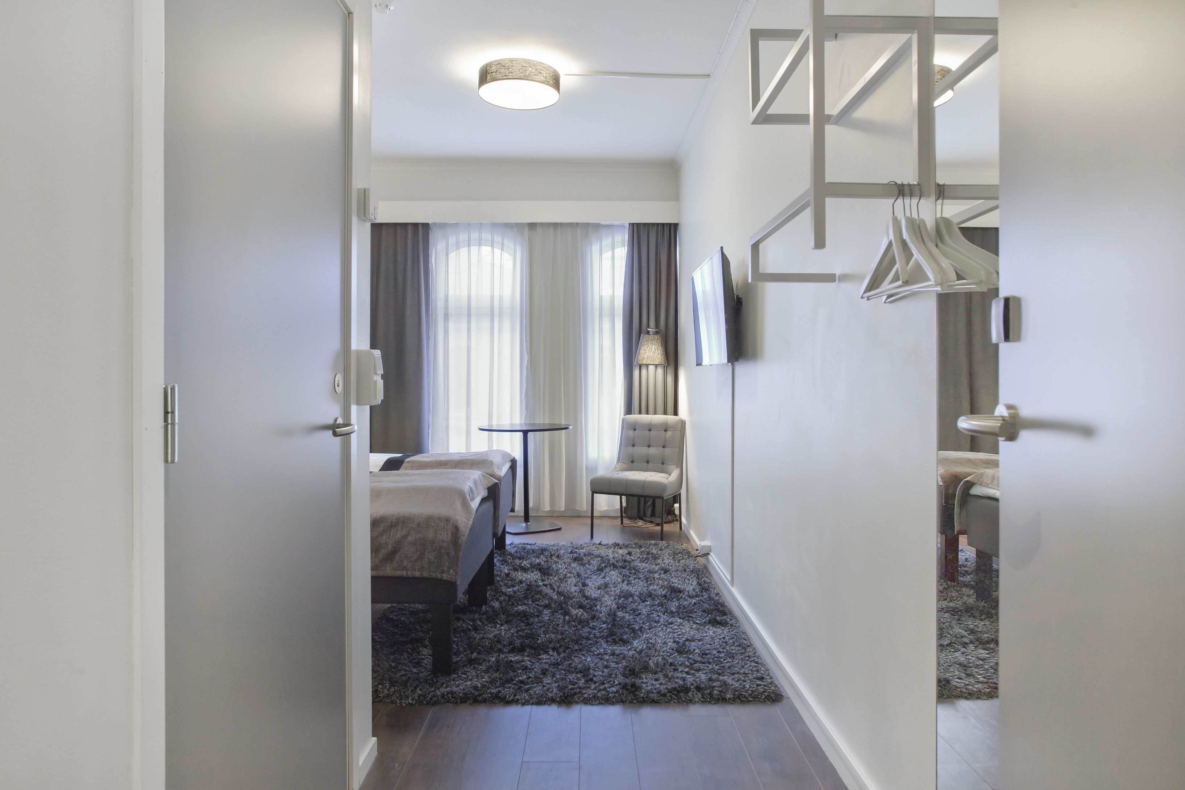 A hotel room with a bed, a chair, a small table, and a TV.
