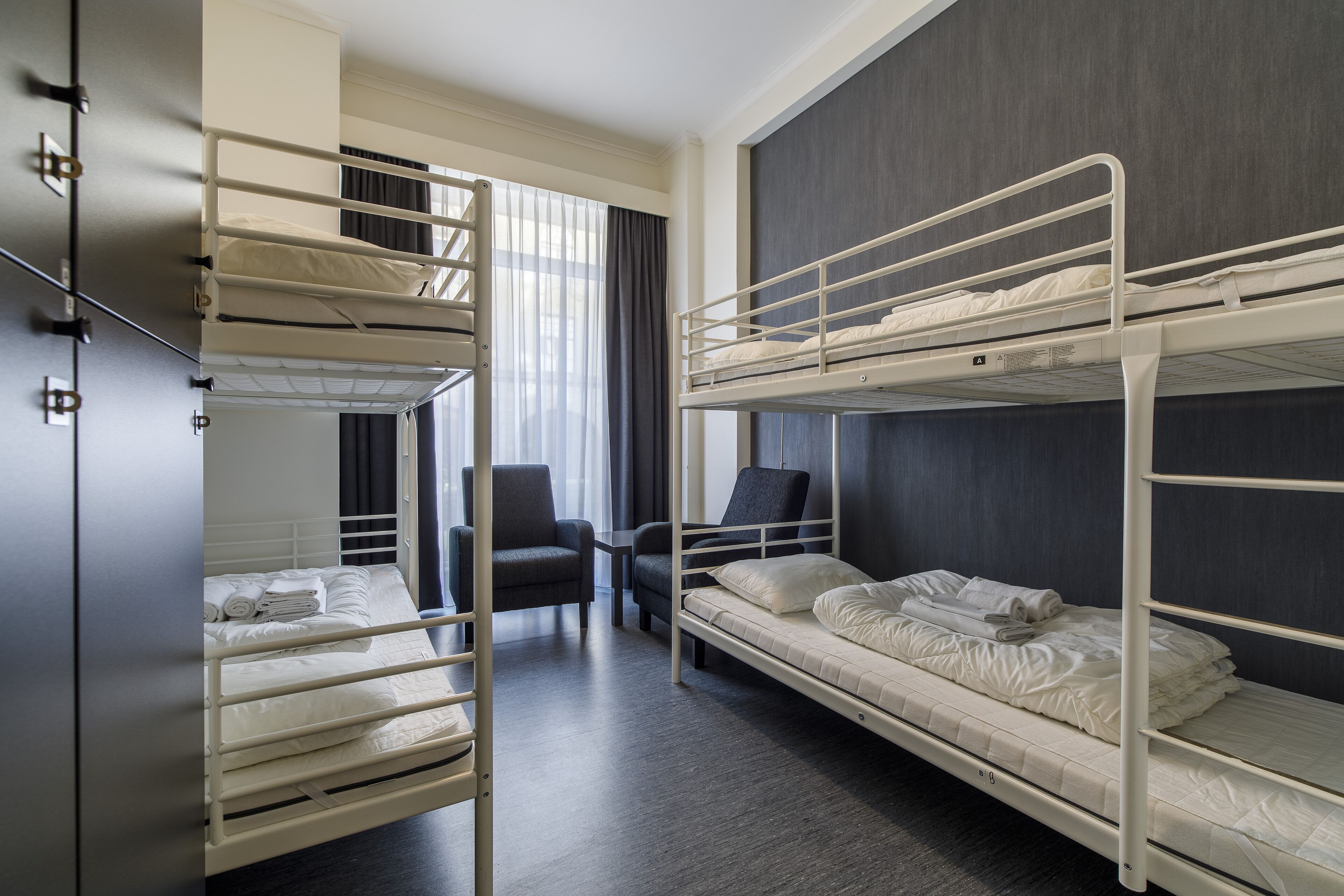 Habitación con literas, un escritorio, una silla, un armario y una ventana con cortinas.