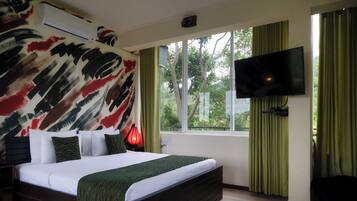 Een slaapkamer met een groot bed, een flatscreen televisie aan de muur en een raam met gordijnen.