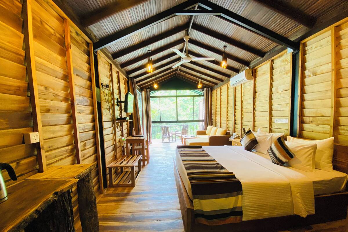 Quarto de cabana de tronco com uma cama, uma escrivaninha e uma cadeira.